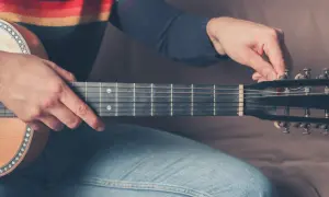 Dłoń stroi gitarę 12 strunową, naciągając struny.