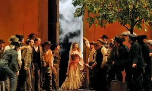 Scena z opery Carmen, gdzie kompozytor Bizet stworzył niezapomnianą postać cyganki. Wokół niej tłum mężczyzn w strojach z epoki.