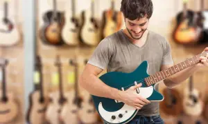 Młody mężczyzna wybiera **jaką gitarę elektryczną na początek** w sklepie muzycznym.