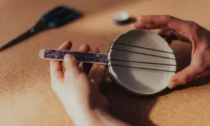 Ręce składają prosty instrument perkusyjny: patyczek z ozdobnym papierem i miseczka z gumkami. Oto jak zrobić instrument perkusyjny!