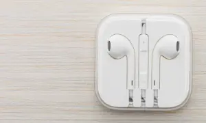 Białe słuchawki w etui. Czy do iPhone pasują inne słuchawki? Tak, ale te są oryginalne.