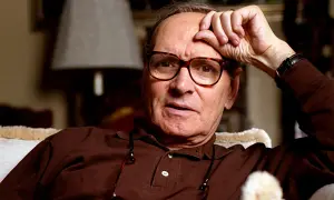Ennio Morricone, genius kompozytor muzyki do **ennio morricone filmy**, zamyślony z ręką na czole.