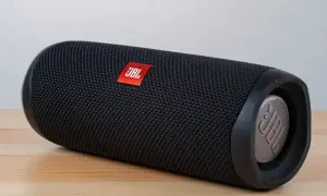 Czarny głośnik JBL na drewnianym blacie. Czy głośnik bluetooth można podłączyć do komputera? Tak, ten model oferuje taką możliwość.