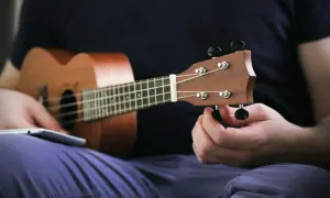 Dłoń kręci kluczem, strojenie ukulele przed graniem.