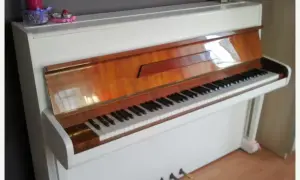 Białe pianino z drewnianymi elementami. Zastanawiasz się, ile kosztuje strojenie pianina?