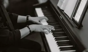 Dłonie grające na pianinie, tworząc melancholijną dumkę. Na nadgarstku bransoletka z krzyżykiem.
