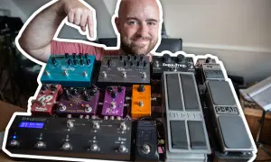 Uśmiechnięty mężczyzna pokazuje swoją bogatą kolekcję efektów gitarowych, prezentując ich kolejność na pedalboardzie.