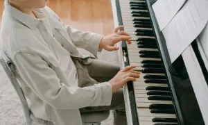 Chłopiec ćwiczy wprawkę dla pianisty, skupiony na nutach.