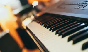 Klawiatura keyboardu, gotowa do zagrania popularnych piosenek. Ciepłe światło otoczenia tworzy przytulną atmosferę.