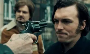 Scena z filmu, gdzie gangster celuje z rewolweru. Może to być moment z "Jak pokochałam gangstera", pełen napięcia i niepewności.