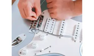 Ręce zakładają struny do gitary elektrycznej. Dowiedz się, jak założyć struny do gitary klasycznej, by cieszyć się nowym brzmieniem.