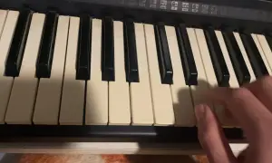 Dłoń gra akordy na keyboardzie, tworząc muzykę.