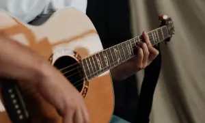 Dłoń grająca na gitarze akustycznej. Zastanawiasz się, ile trwa nauka gry na gitarze? To zależy od Ciebie!