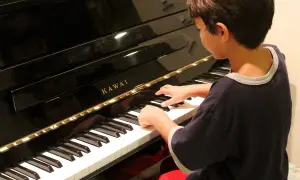 Chłopiec z zapałem gra na pianinie Kawai. Może kiedyś skomponuje własną melodię i powie: "zagraj to sam".