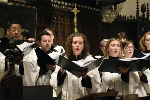 Chór śpiewa "Miserere", skupiony na tekście w księgach.