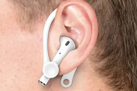Ucho z białą słuchawką AirPods i zaczepem, pokazujące, jak poprawnie nosić Airpods dla lepszego dopasowania.