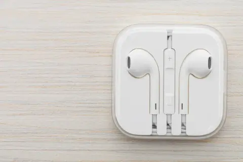 Białe słuchawki w etui. Czy do iPhone pasują inne słuchawki? Tak, ale te są oryginalne.