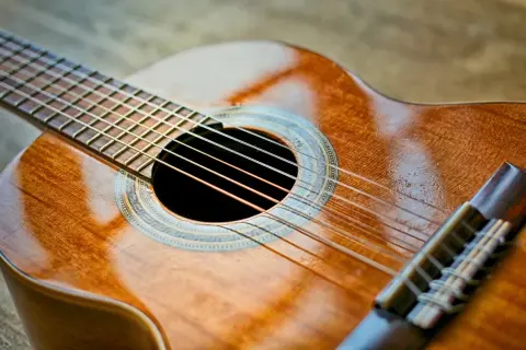 Piękna gitara klasyczna, idealna do nauki gry. Jej ciepłe drewno i błyszczące struny zapraszają do muzykowania.