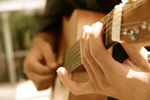 Dłonie grające na gitarze, tworząc dźwięki, które mogą wywołać uczucie lacrimosa.
