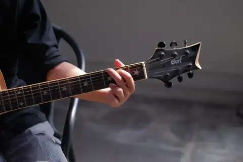 Dłoń grająca akord na gitarze klasycznej. Gwiazdki na gryfie dodają uroku, a całość przywodzi na myśl najładniejsze utwory na gitarę klasyczną.