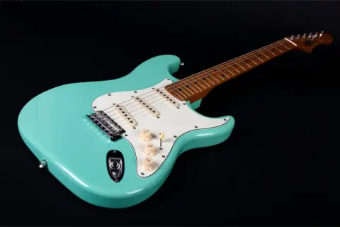 Turkusowa gitara elektryczna, idealna do nauki jak grać na gitarze elektrycznej. Ma biały pickguard i drewnianą podstrunnicę.