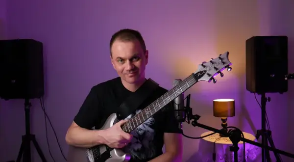 Mężczyzna z gitarą elektryczną, gotowy do nauki gry na gitarze online za darmo.