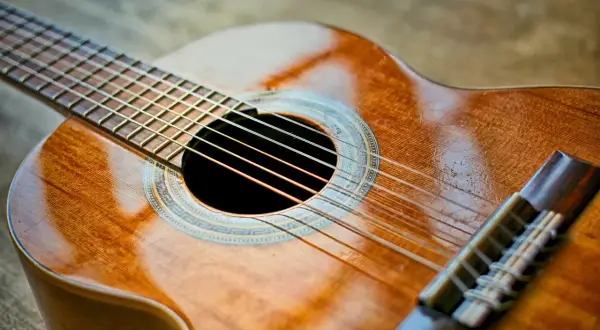 Piękna gitara klasyczna, idealna do nauki gry. Jej ciepłe drewno i błyszczące struny zapraszają do muzykowania.