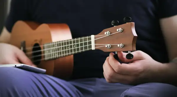 Dłoń kręci kluczem, strojenie ukulele przed graniem.
