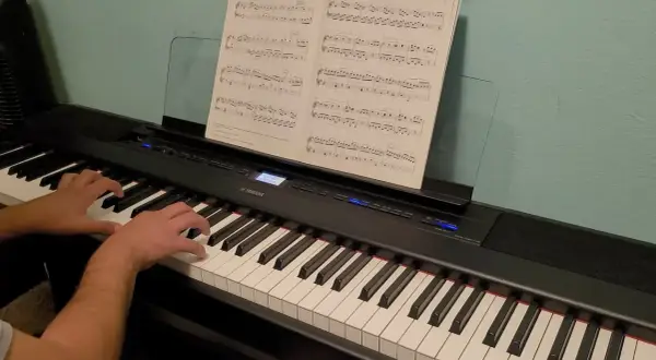 Palce pianisty tańczą po klawiszach, tworząc melodię. Nuty na pulpicie wskazują drogę.