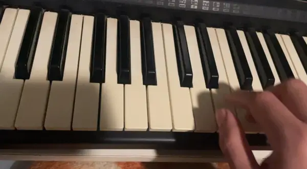 Dłoń gra akordy na keyboardzie, tworząc muzykę.
