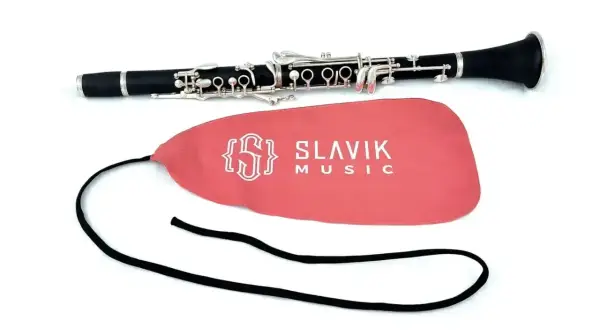 Czarny klarnet, jaki to instrument, leży obok różowego pokrowca z logo Slavik Music.