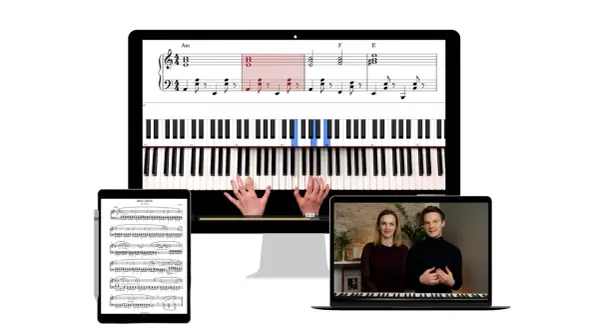 Kolędy nuty na pianino wyświetlane na ekranie komputera, tabletu i laptopa. Widać klawiaturę, ręce grające i fragmenty nut.