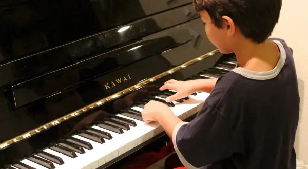 Chłopiec z zapałem gra na pianinie Kawai. Może kiedyś skomponuje własną melodię i powie: "zagraj to sam".