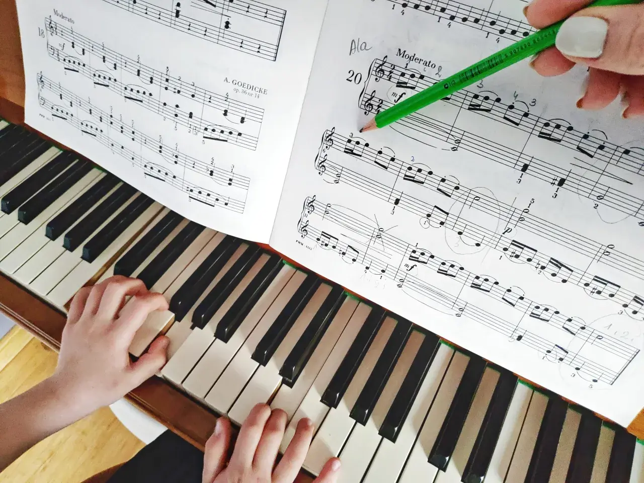 Dziecko uczy się grać proste melodie na pianino. Zielony ołówek wskazuje nuty w zeszycie.