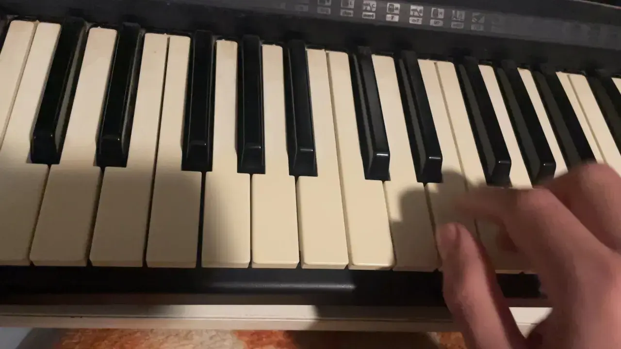 Dłoń gra akordy na keyboardzie, tworząc muzykę.