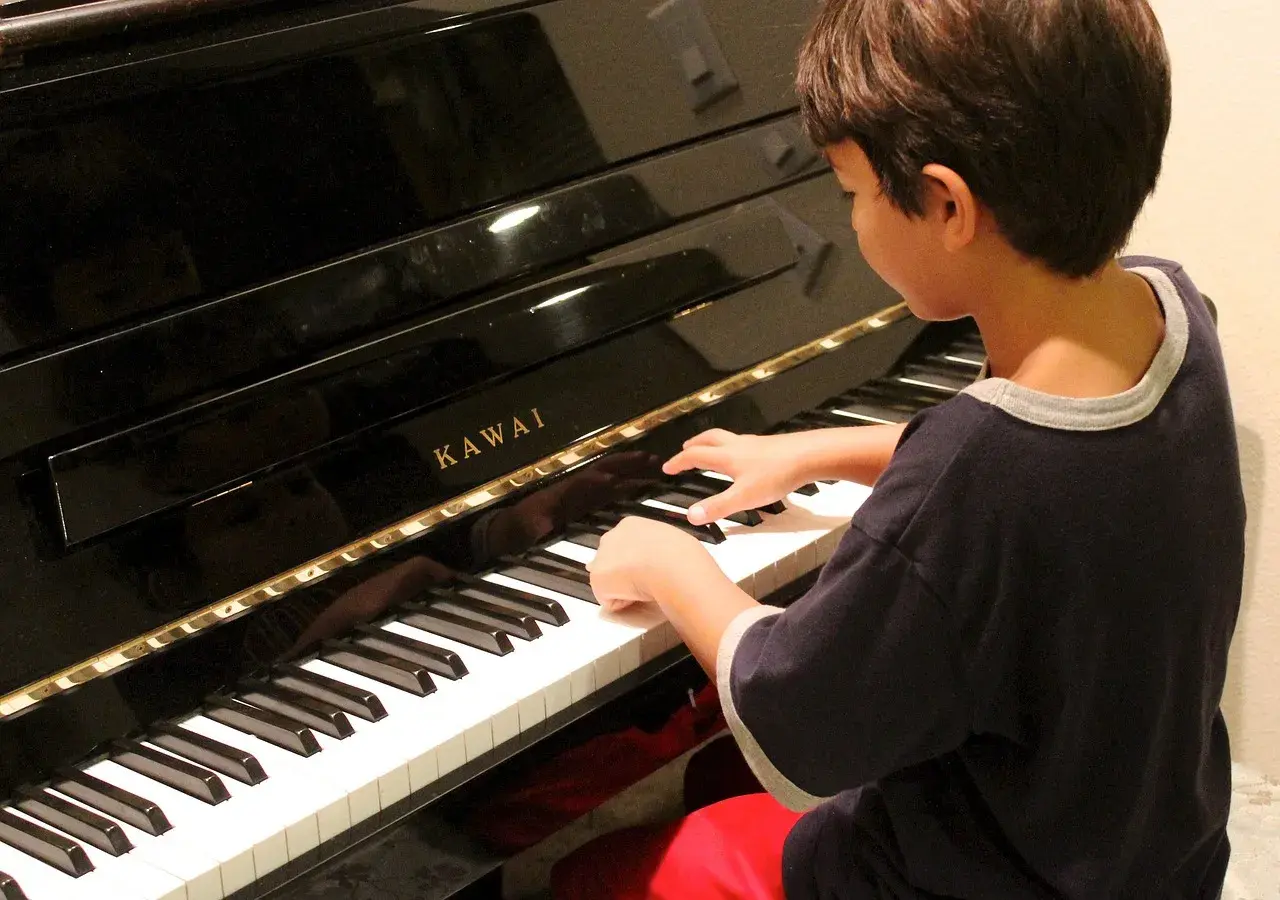 Chłopiec z zapałem gra na pianinie Kawai. Może kiedyś skomponuje własną melodię i powie: "zagraj to sam".