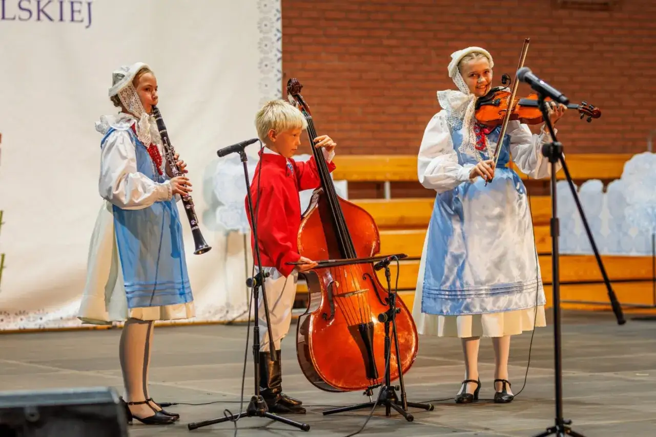 Dzieci w strojach ludowych grają na instrumentach: skrzypcach, kontrabasie i klarnecie. Chcą pokazać, że każdy może zagraj to sam!