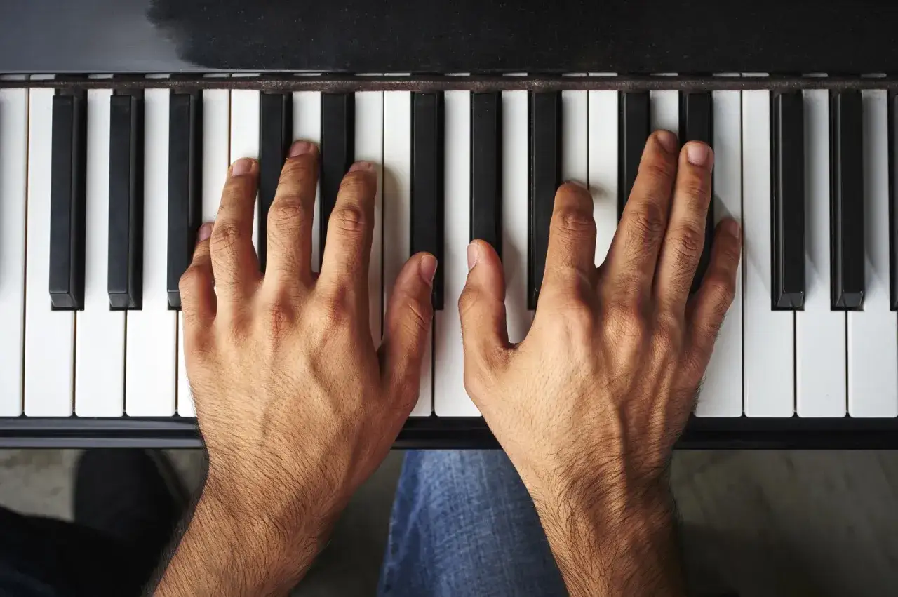 Palce pianisty na klawiaturze tworzą melodię.
