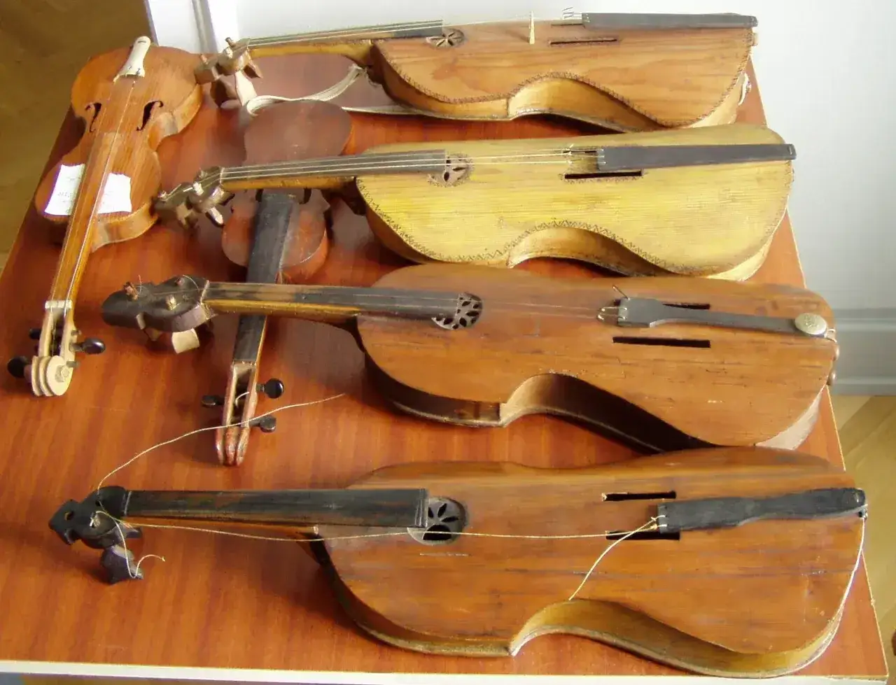 Rząd starych instrumentów smyczkowych, w tym pudło skrzypiec.