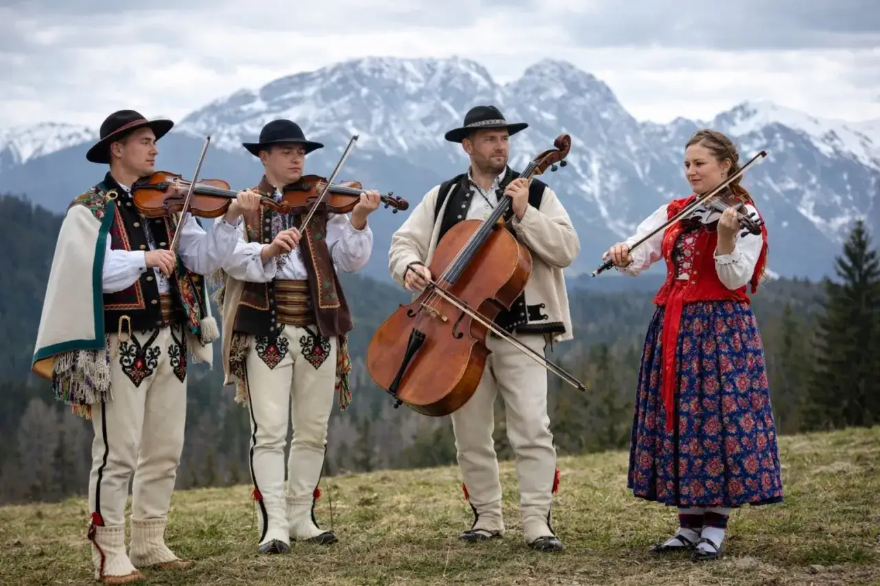 Muzycy w strojach ludowych grają na instrumentach. W murowanej piwnicy nuty mogłyby brzmieć równie pięknie, ale góry dodają im magii.
