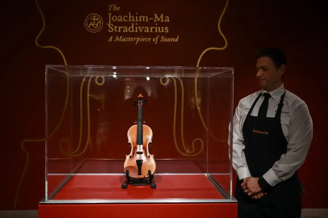 Joachim-Ma Stradivarius, najdroższe skrzypce na świecie, w gablocie. Obok stoi pracownik Sotheby's.