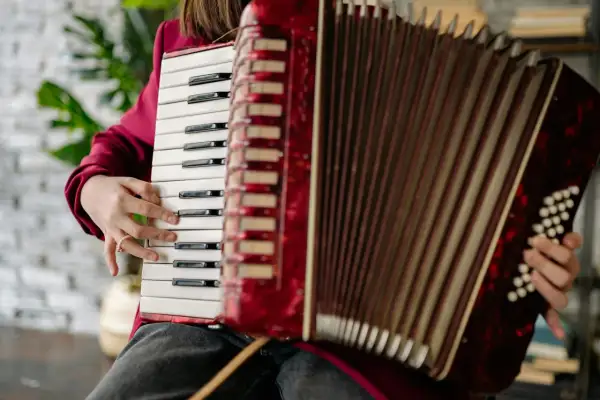 Dłoń gra na klawiszach akordeonu, pokazując, jaki to instrument.