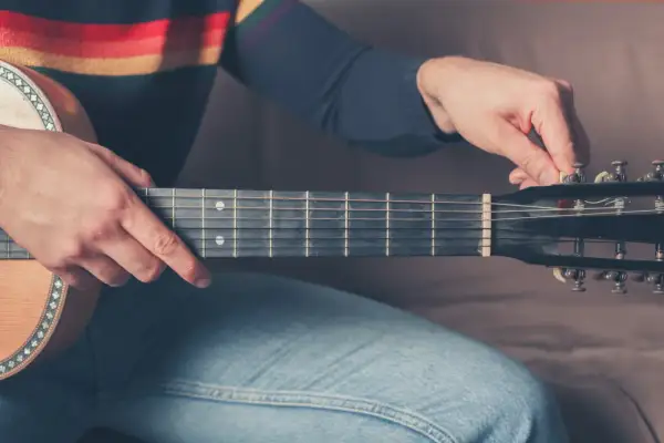 Dłoń stroi gitarę 12 strunową, naciągając struny.
