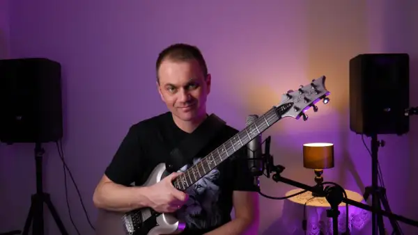 Mężczyzna z gitarą elektryczną, gotowy do nauki gry na gitarze online za darmo.