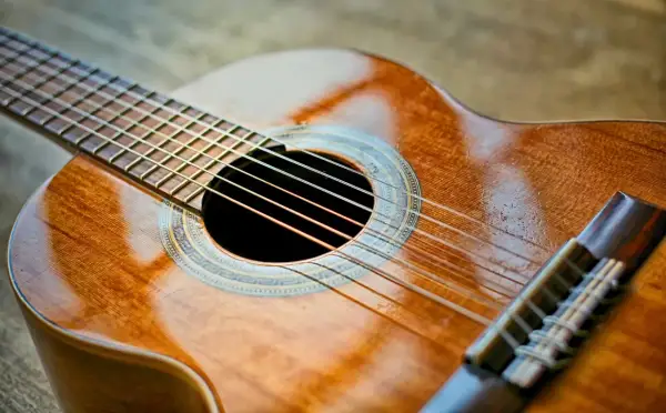 Piękna gitara klasyczna, idealna do nauki gry. Jej ciepłe drewno i błyszczące struny zapraszają do muzykowania.