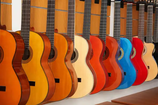 Rząd kolorowych gitar akustycznych, od pomarańczowej po czerwoną i niebieską, prezentuje różne rodzaje gitar akustycznych.