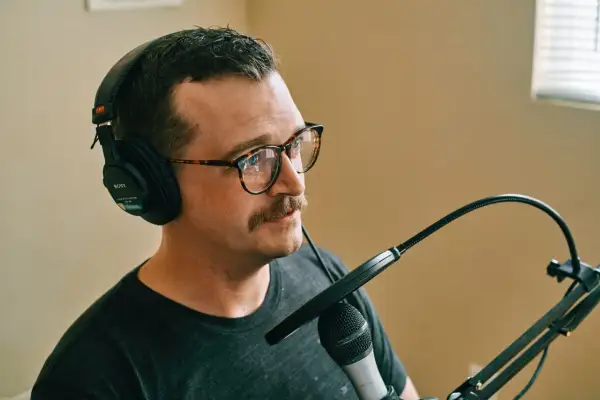 Mężczyzna w okularach i słuchawkach przygotowuje się do nagrywania mikrofonu.