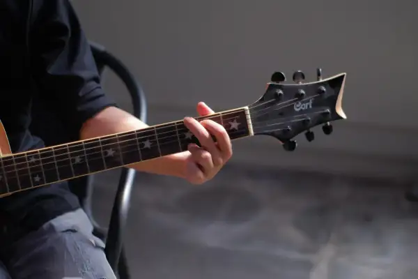 Dłoń grająca akord na gitarze klasycznej. Gwiazdki na gryfie dodają uroku, a całość przywodzi na myśl najładniejsze utwory na gitarę klasyczną.