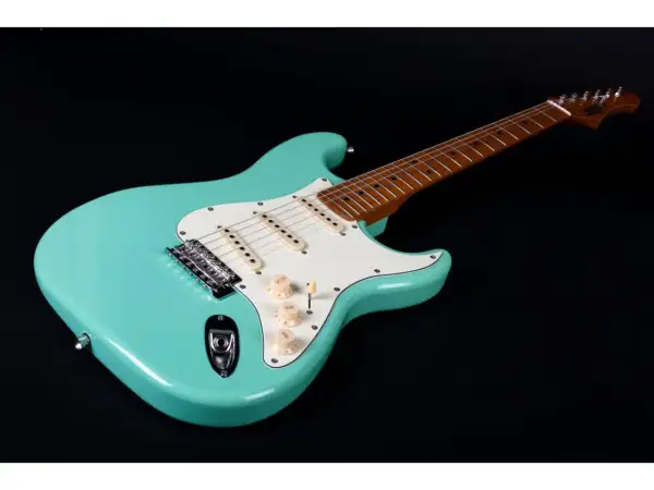 Turkusowa gitara elektryczna, idealna do nauki jak grać na gitarze elektrycznej. Ma biały pickguard i drewnianą podstrunnicę.