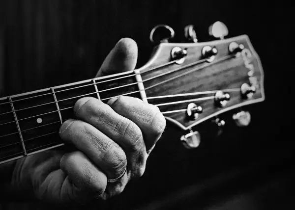 Dłoń z pierścionkiem na serdecznym palcu chwyta akord na gryfie gitary. Powstają piękne utwory na gitarę.
